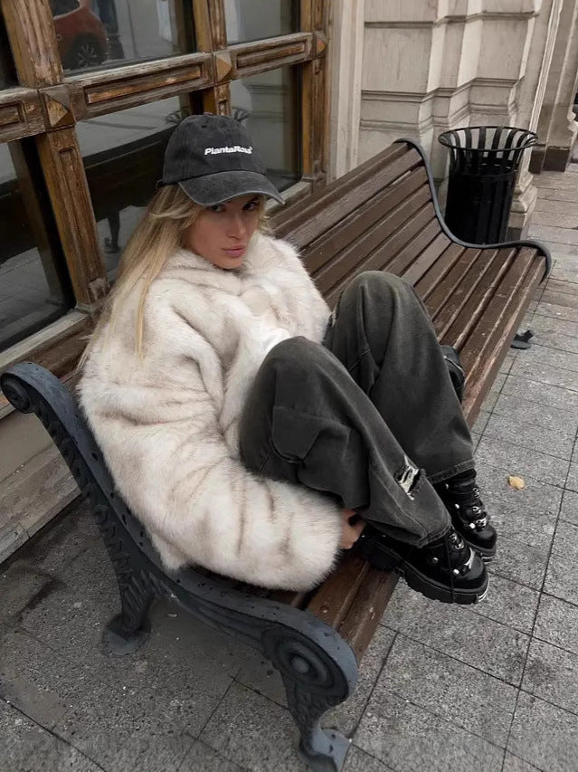Woman wearing a Fluffy Fox Fur Coat Women Loose Elegant Winter, seated on a bench in urban setting.