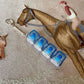Clickie Keychain organized with blue containers on a decorative horse-patterned background.
