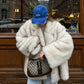 Fluffy Fox Fur Coat Women Loose Elegant Winter in a snowy urban setting, paired with a blue cap and a designer handbag.