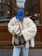 Fluffy Fox Fur Coat Women Loose Elegant Winter worn with a blue cap and a designer handbag in an urban setting.