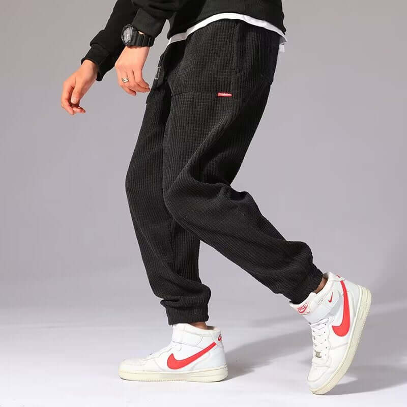 Mens Casual Pants model walking in stylish outfit with white sneakers and black pants.
